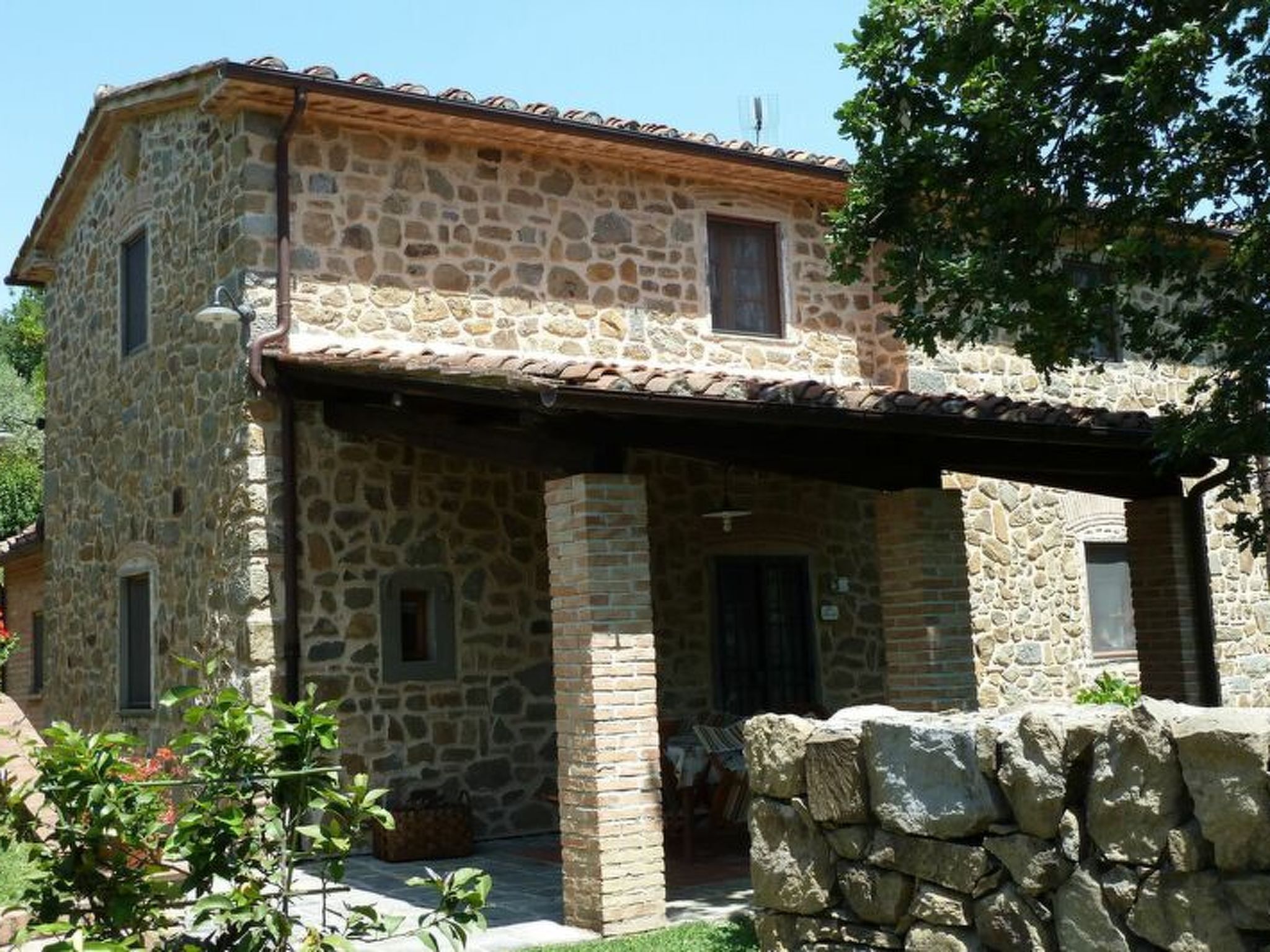 A stone building with a covered porch and a small window.