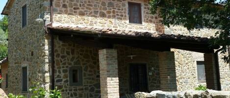 A stone building with a covered porch and a small window.