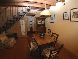A dining area with a wooden table, chairs, a hanging light fixture, a staircase, and a kitchen in the background. - Le Case Di Carla Zizzola by Interhome (Borgo a Buggiano)