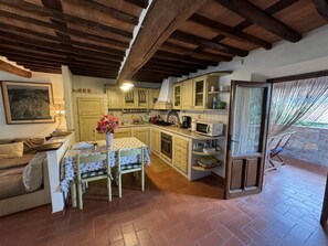 A cozy kitchen with wooden beams, a dining table with chairs, and a view of the outdoors. - Casa Max by Interhome (Capannori)