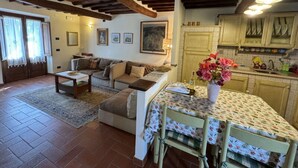 A cozy living room with a sofa, a coffee table, and a dining area with a table set for two. - Casa Max by Interhome (Capannori)
