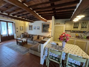 A cozy living room with a sofa, a coffee table, and a dining area with a table set for two. - Casa Max by Interhome (Capannori)
