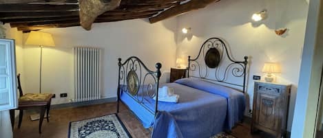 Une chambre à coucher avec un lit, deux tapis, un radiateur, une lampe et une armoire en bois.