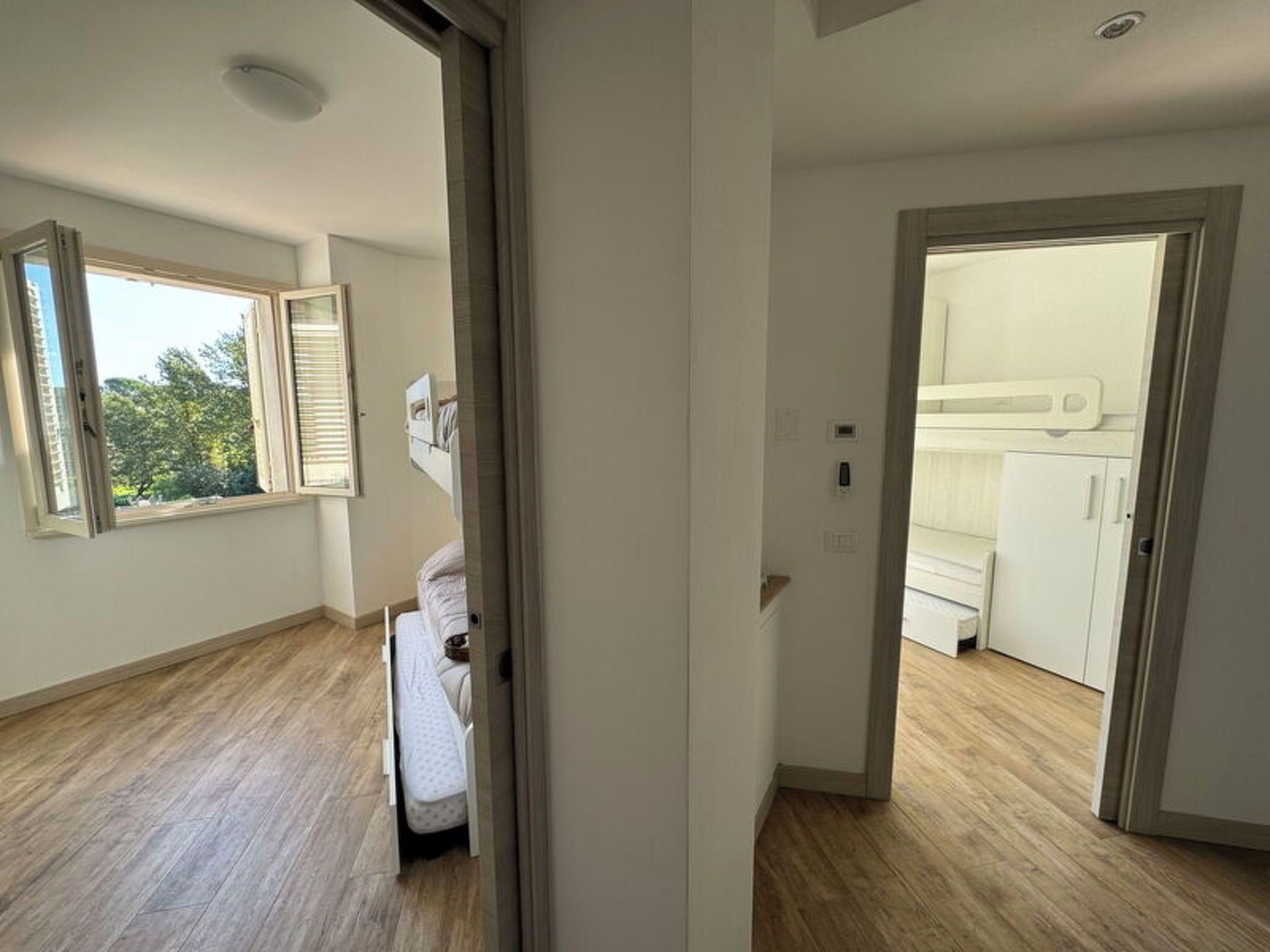 Una habitación con una cama, una ventana y una puerta que da a otra habitación.