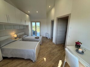 Un dormitori amb dos llits, una taula de treball i vista a l'exterior.