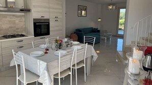 Une cuisine moderne avec un coin repas, un canapé et un escalier.