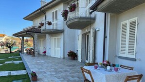 Un bâtiment doté d’un patio couvert, d’un espace extérieur aménagé pour s’asseoir et d’une table dressée pour le repas.