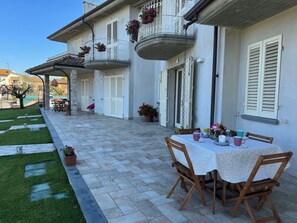 A building with a covered patio, outdoor seating, and a table set for dining. - Villa al Glicine by Interhome (Altopascio)