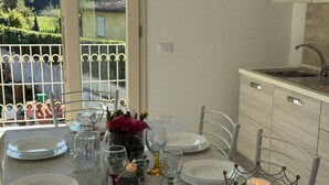 Une table à manger dressée avec des assiettes, des verres et un chandelier servant de centre de table, dans une cuisine donnant sur une fenêtre.