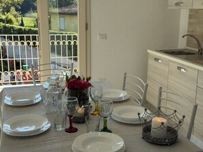 A dining table set with plates, glasses, and a candle centerpiece in a kitchen with a window view. - Villa al Glicine by Interhome (Altopascio)