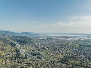 Ein weiter Blick auf eine Küstenstadt mit einer markanten Brücke, üppigem Grün und einem fernen Gewässer.