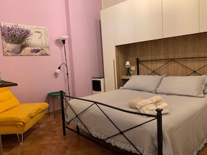 A bedroom with a bed, a chair, a lamp, and a speaker. - Bocelli by Interhome (Peccioli)