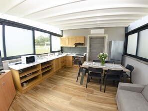 A modern kitchen with wooden cabinets, a dining table with chairs, and a grey sofa. - Tenuta Il Giardino Proprietà by Interhome (Capannori)