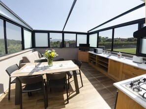 A modern kitchen with a dining area, large windows, and a view of the outdoors. - Tenuta Il Giardino Proprietà by Interhome (Capannori)