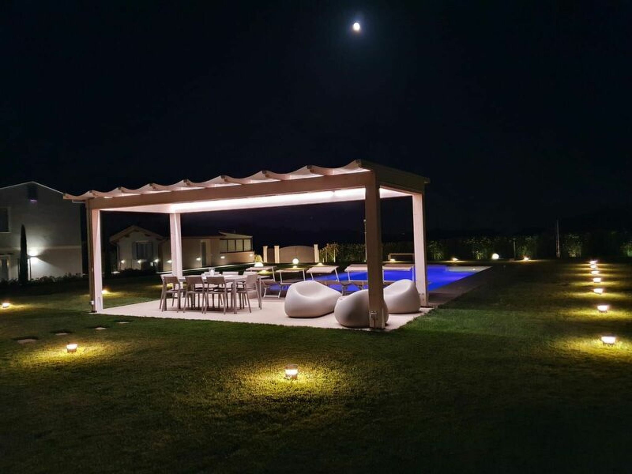 A covered outdoor area with a pool, seating, and a pergola.