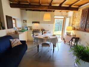 A cozy kitchen with a dining table, chairs, and a blue sofa. - Il Cantuccio Proprietà by Interhome (Colognora)
