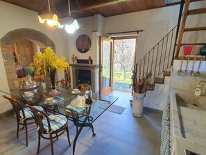 A dining area with a glass table, chairs, a vase with yellow flowers, a fireplace, and a view of the outdoors. - Il Cantuccio Proprietà by Interhome (Colognora)