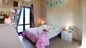 A bedroom with a bed, bedside table, nightstand, and a wall with a bird mural. - Ai Salici by Interhome (Lari)