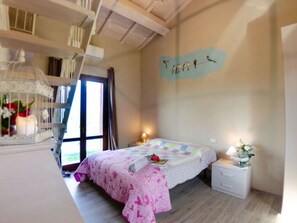 A bedroom with a bed, bedside table, nightstand, and a wall with a bird mural. - Ai Salici by Interhome (Lari)