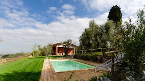 A backyard with a wooden deck, a swimming pool, and a covered outdoor seating area. - Ai Salici by Interhome (Lari)