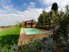 A backyard with a wooden deck, a swimming pool, and a covered outdoor seating area. - Ai Salici by Interhome (Lari)