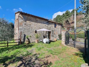 A stone building with a small patio area, a metal gate, and a clear sky. - Il Cantuccio by Interhome (Colognora)