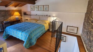Un dormitorio con una cama, una mesita de noche, una lámpara y una escalera.