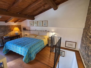 Ein Schlafzimmer mit einem Bett, einem Nachttisch, einer Lampe und einer Treppe.