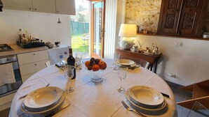 Mesa con vajilla, cubiertos y frutero, con una pared de piedra y armarios de madera al fondo.