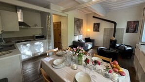 Un comedor con una mesa dispuesta para cuatro, una cocina con electrodomésticos modernos y una sala de estar con un sofá y una lámpara.