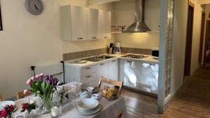 Una cocina moderna con armarios blancos, una campana extractora de acero inoxidable y un comedor listo para una comida.