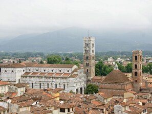 Eine historische Stadt mit einem markanten Glockenturm und Dom, umgeben von traditionellen Gebäuden mit Terrakotta-Dächern.