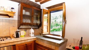 Una cucina con mobili in legno, un piano cottura a gas, un tostapane e una finestra vista verde.