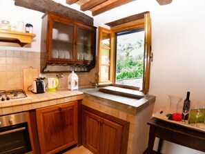 Eine Küche mit Holzausstattung, einem Gaskochfeld, einem Toaster und einem Fenster mit Blick auf Grünflächen.