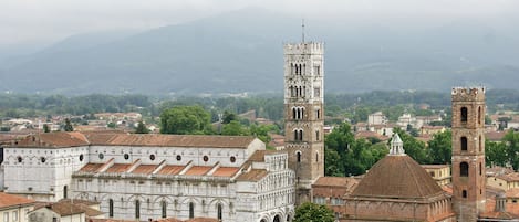 Uma cidade histórica com uma torre de sino imponente e catedral, rodeada por edifícios tradicionais com telhados de terracota.