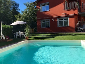 A swimming pool with a red building in the background. - Borgo Di Zacco by Interhome (La Sassa)