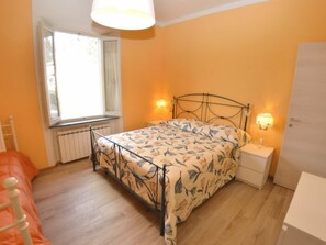 A bedroom with a bed, bedside tables, a window, and a radiator. - Borgo Di Zacco by Interhome (La Sassa)