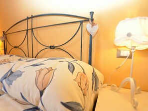 A bed with a floral-patterned duvet, a heart-shaped decoration on the headboard, and a bedside lamp. - Borgo Di Zacco by Interhome (La Sassa)