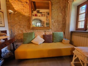 A cozy room with a sofa, a mirror, a bookshelf, and a window. - Il Cantuccio by Interhome (Colognora)