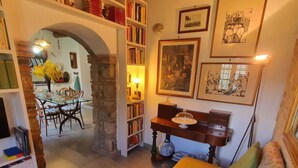 Ein gemütliches Wohnzimmer mit einem gelben Sofa, einem Bücherregal, einem Essbereich mit Tisch und Stühlen und einem Steingewölbe.
