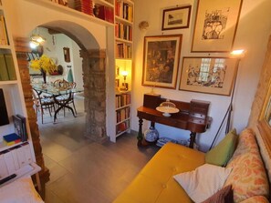 Ein gemütliches Wohnzimmer mit einem gelben Sofa, einem Bücherregal, einem Essbereich mit Tisch und Stühlen und einem Steingewölbe.