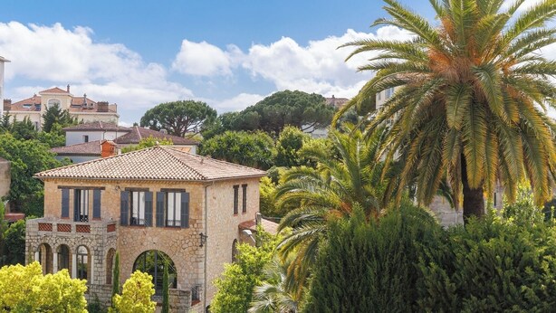 A stone building with a tiled roof, arched windows, and a small balcony. - Upstays Bright 1BR 50m² with terrace Cannes center (Cannes)