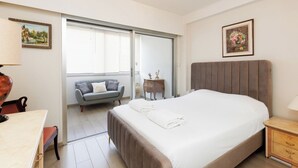 A bedroom with a bed, a sofa, a small table, and a nightstand. - Upstays Bright 1BR 50m² with terrace Cannes center (Cannes)