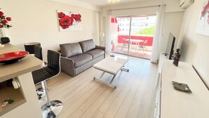 A modern living room with a sofa, coffee table, and a dining area with chairs and a table. - Upstays Bright 1BR 50m² with terrace Cannes center (Cannes)