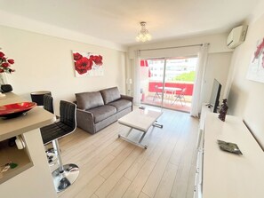 A modern living room with a sofa, coffee table, and a dining area with chairs and a table. - Upstays Bright 1BR 50m² with terrace Cannes center (Cannes)