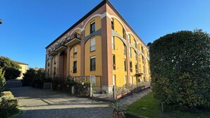 Un immeuble à plusieurs étages, doté d’une façade jaune, d’une allée pavée et d’une pelouse bien entretenue.