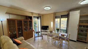 Un salon comprenant un canapé, une table à manger, des chaises, un téléviseur et un meuble.