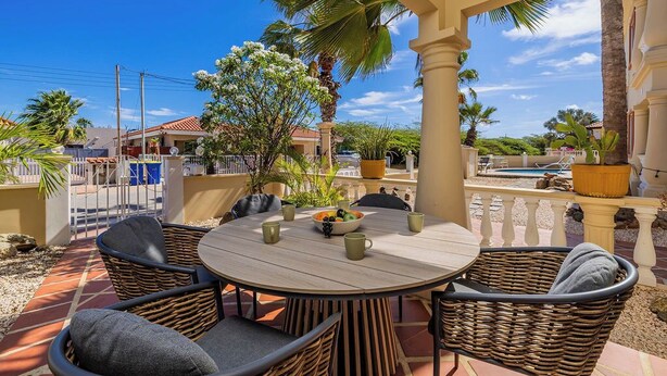Een terras met rieten meubels, een ronde tafel en een schaal fruit.
