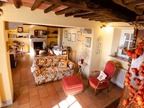 Uma sala de estar aconchegante com um sofá floral, uma poltrona vermelha e uma lareira.