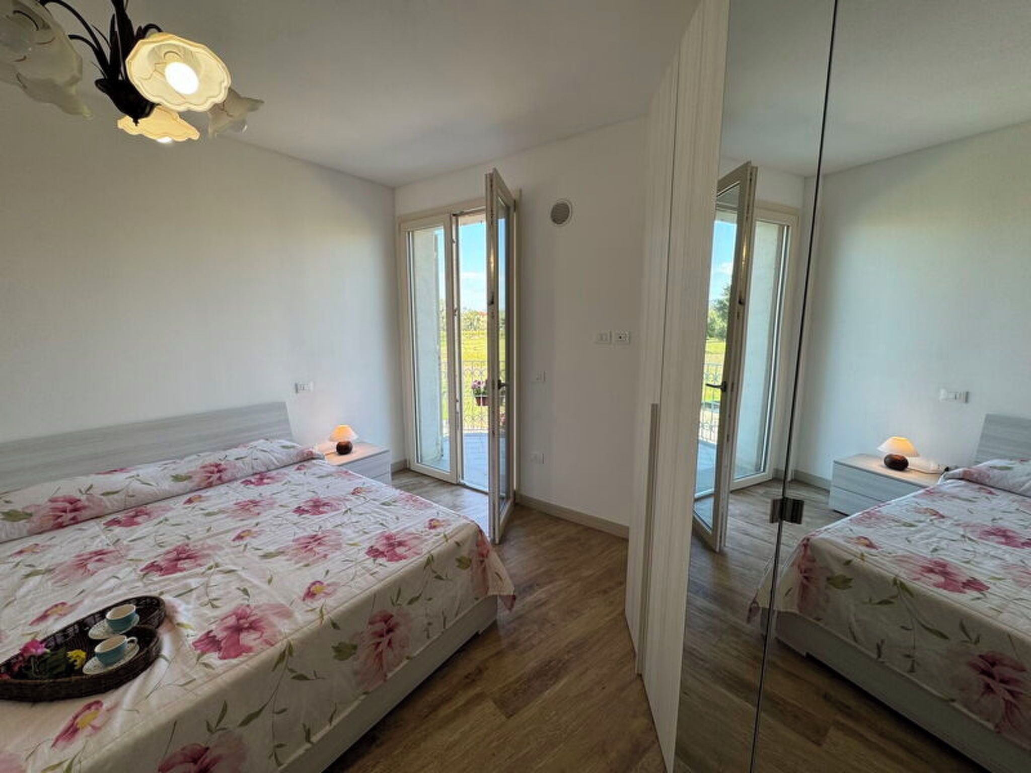Une chambre avec deux lits, un balcon et un grand miroir.